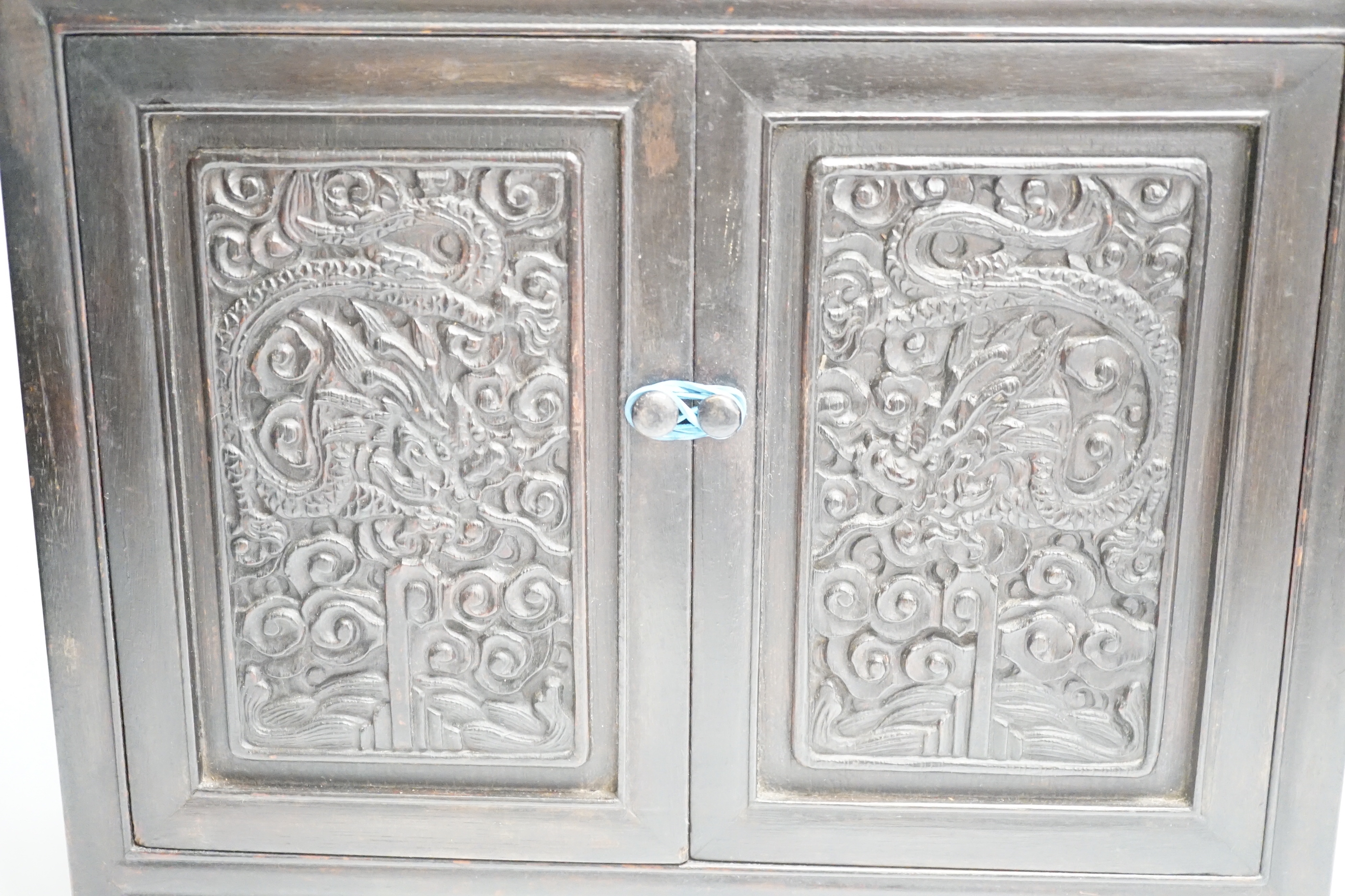 An early 20th century Chinese hongmu cabinet with carved cupboard doors, 61cm high